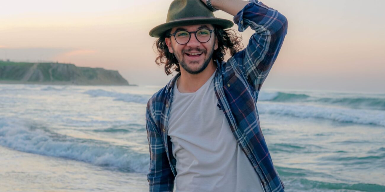 Guy on beach holding hat